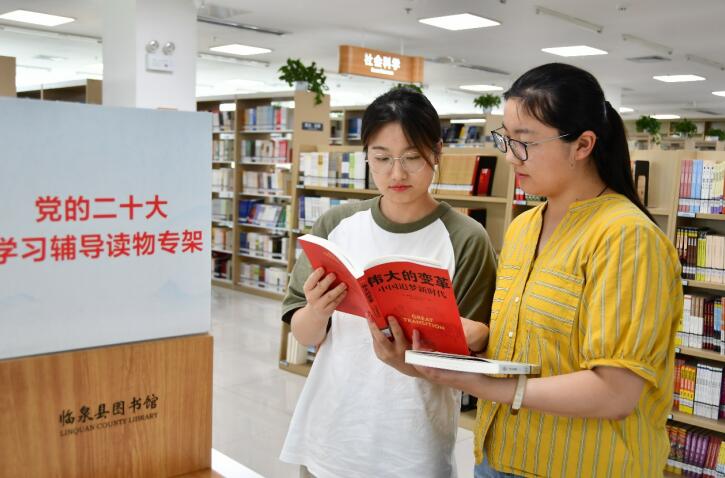 兩名青年在黨的二十大學習輔導讀物專架前挑選喜愛的圖書。趙懷勇攝